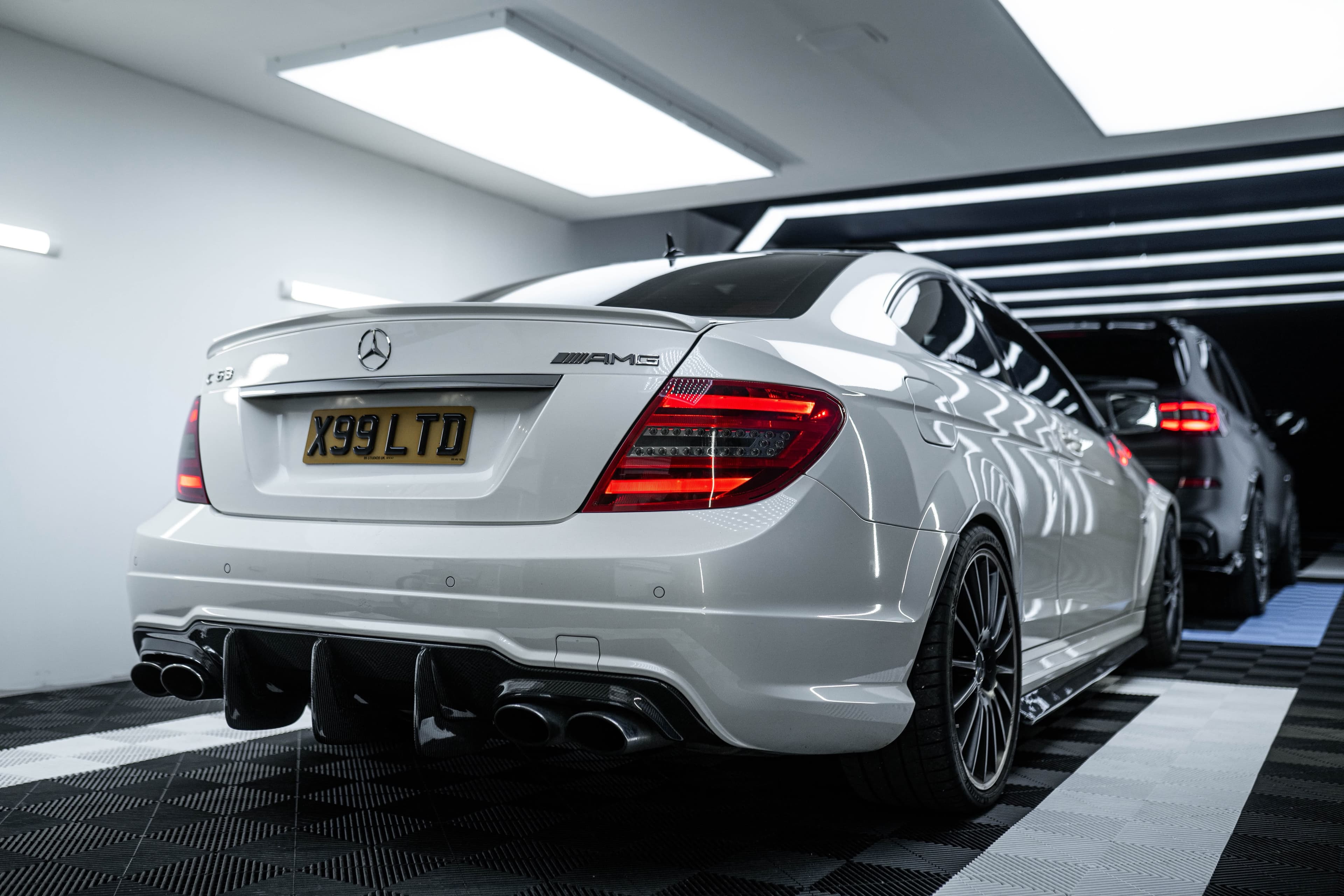 White Mercedes-AMG C63, rear three-quarter on the tiled floor